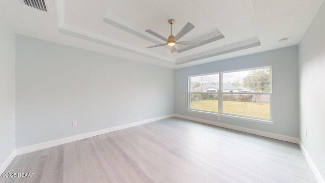 empty room featuring light hardwood / wood-style floors, a raised ceiling, and ceiling fan