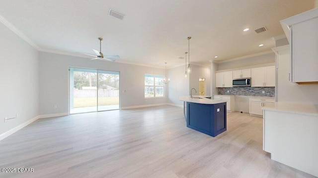 kitchen with tasteful backsplash, crown molding, a kitchen island with sink, and white cabinets