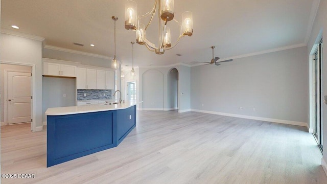 kitchen featuring sink, white cabinetry, an island with sink, decorative backsplash, and decorative light fixtures