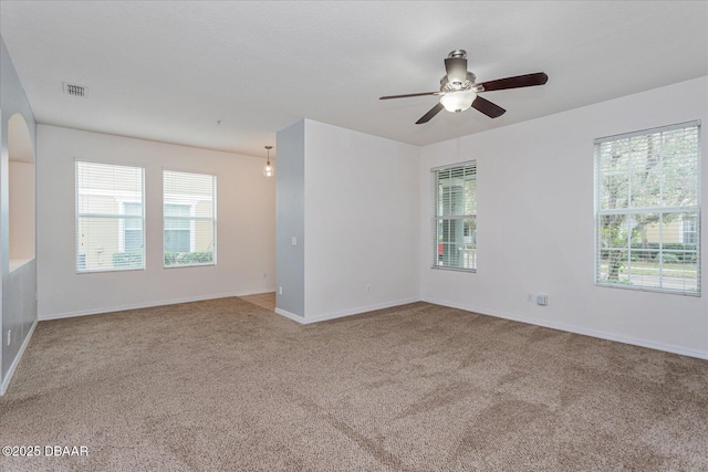 unfurnished room featuring ceiling fan, carpet, and a healthy amount of sunlight