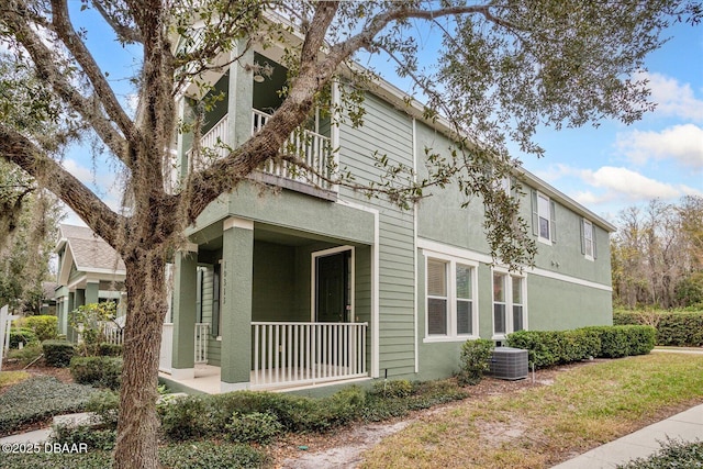 view of front facade featuring covered porch, cooling unit, and a balcony