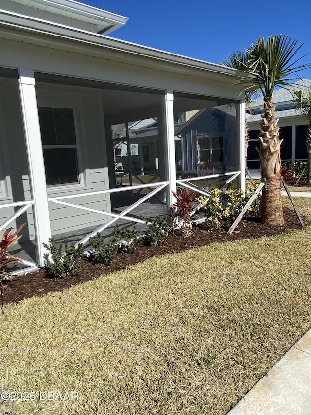 view of side of property featuring a sunroom and a lawn