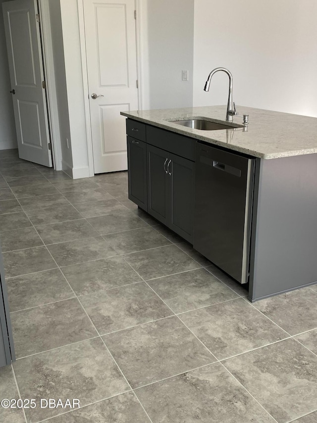 kitchen with light stone counters, sink, dishwasher, and a center island with sink