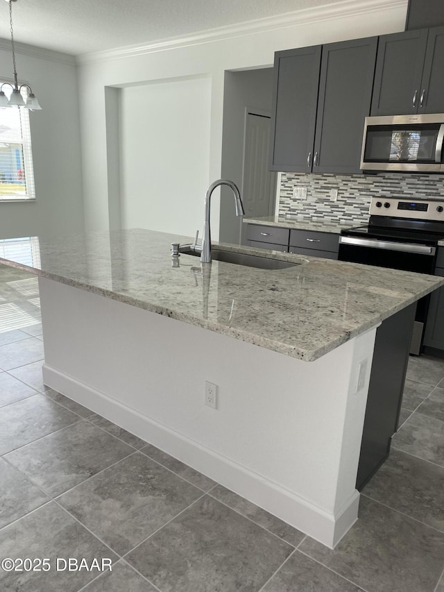 kitchen featuring appliances with stainless steel finishes, an island with sink, hanging light fixtures, and sink