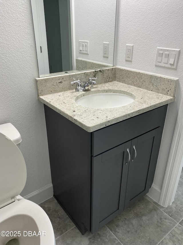 bathroom with toilet, vanity, and tile patterned flooring