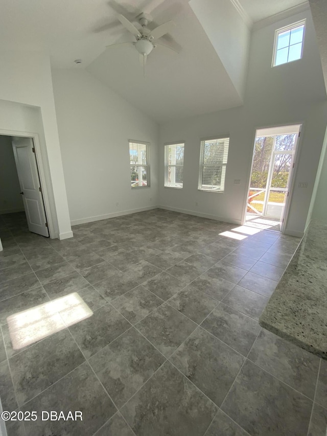 unfurnished living room with ceiling fan, a healthy amount of sunlight, and a towering ceiling