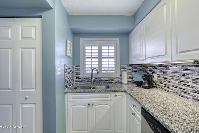 kitchen with white cabinets, backsplash, light stone countertops, and sink