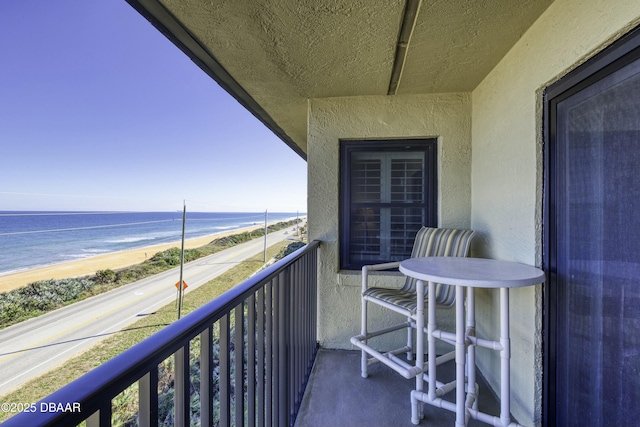 balcony featuring a view of the beach and a water view