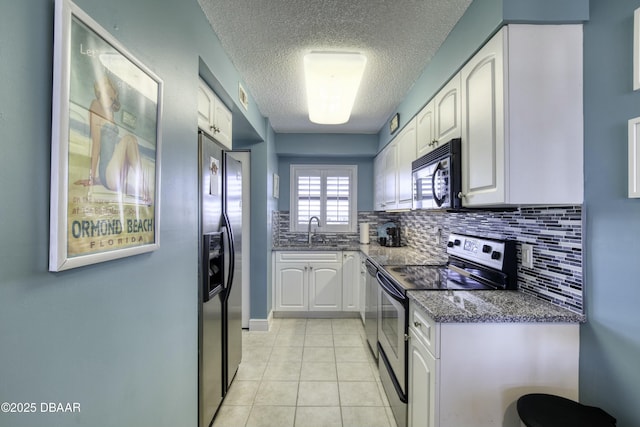 kitchen with white cabinetry, stainless steel appliances, dark stone counters, sink, and light tile patterned flooring