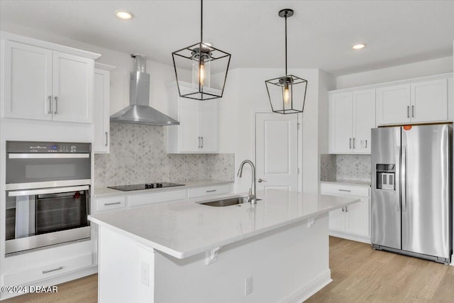 kitchen featuring wall chimney exhaust hood, stainless steel appliances, sink, decorative light fixtures, and white cabinetry