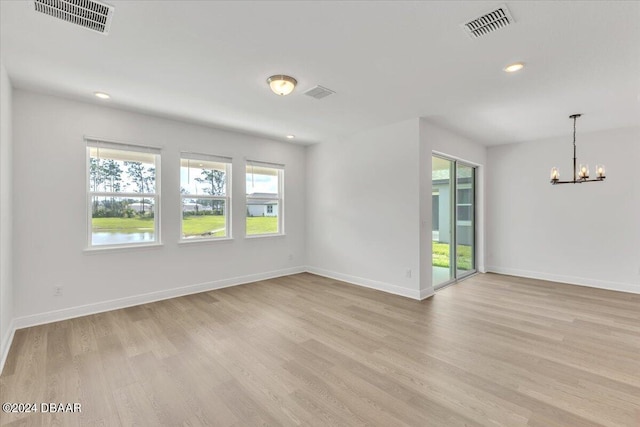 empty room with an inviting chandelier and light hardwood / wood-style flooring