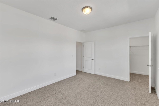 unfurnished bedroom with light colored carpet, a spacious closet, and a closet