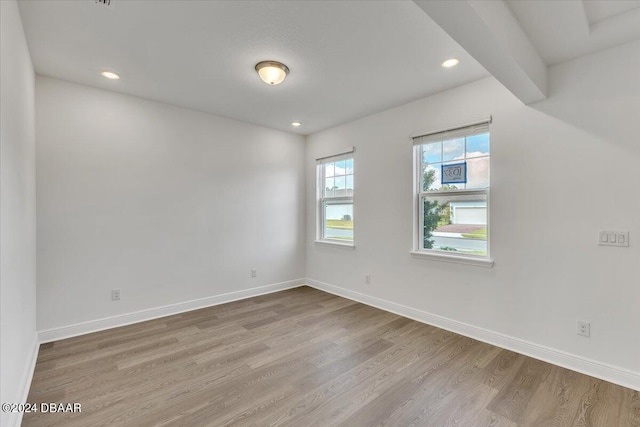 unfurnished room featuring beamed ceiling and wood-type flooring