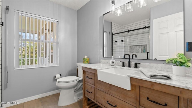 bathroom featuring a stall shower, baseboards, vanity, and toilet