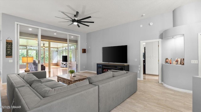 living room featuring a textured ceiling, baseboards, and a ceiling fan