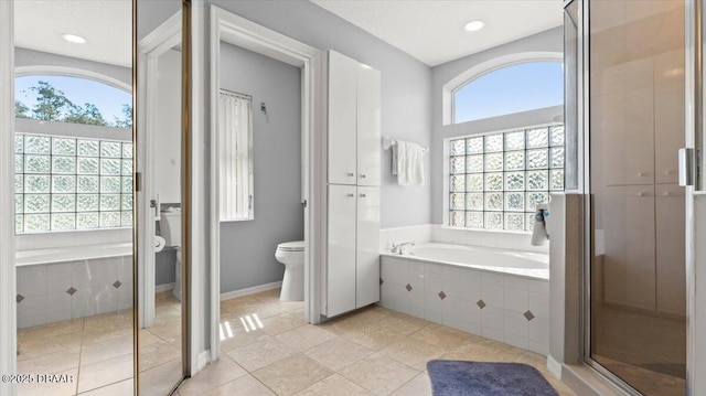 bathroom with a garden tub, toilet, baseboards, a shower stall, and tile patterned floors