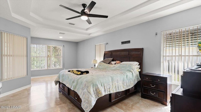 bedroom featuring a ceiling fan, a raised ceiling, visible vents, and baseboards