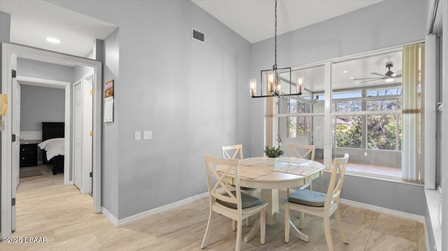 dining space with ceiling fan with notable chandelier, vaulted ceiling, visible vents, and baseboards