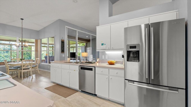 kitchen featuring white cabinets, appliances with stainless steel finishes, light countertops, pendant lighting, and a sink