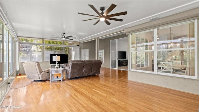 living room with a ceiling fan, visible vents, and wood finished floors