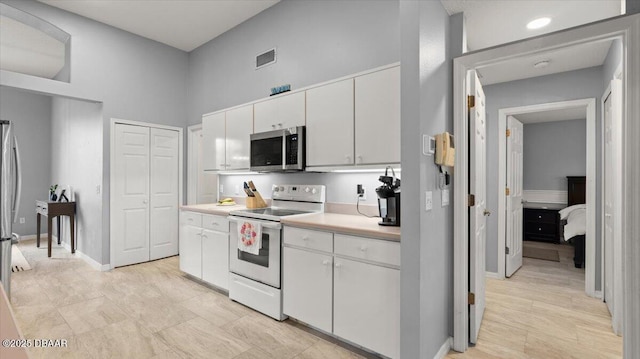 kitchen with visible vents, white cabinets, electric stove, stainless steel microwave, and light countertops