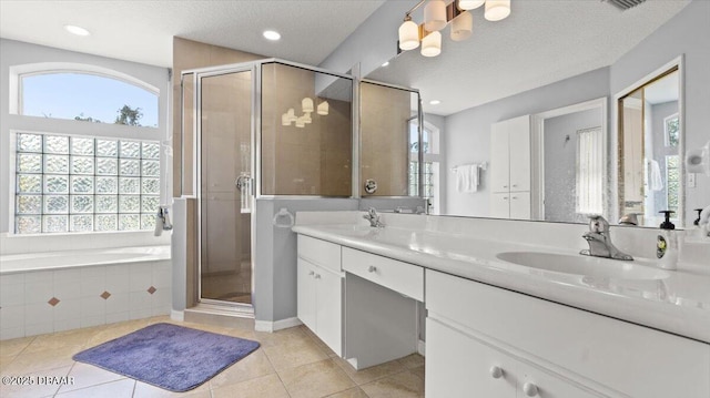 full bathroom featuring double vanity, a stall shower, tile patterned floors, a textured ceiling, and a sink