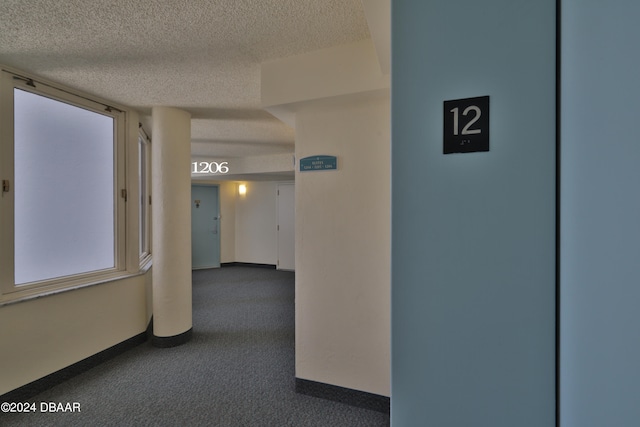 hallway with a textured ceiling and carpet flooring