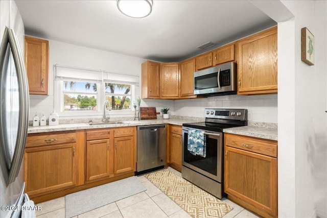 kitchen with backsplash, appliances with stainless steel finishes, sink, and light tile patterned floors