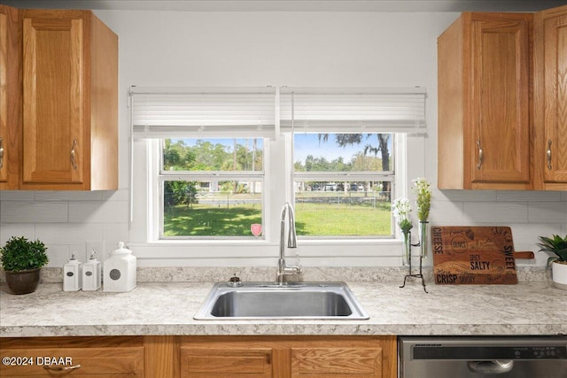 kitchen with stainless steel dishwasher, sink, and tasteful backsplash