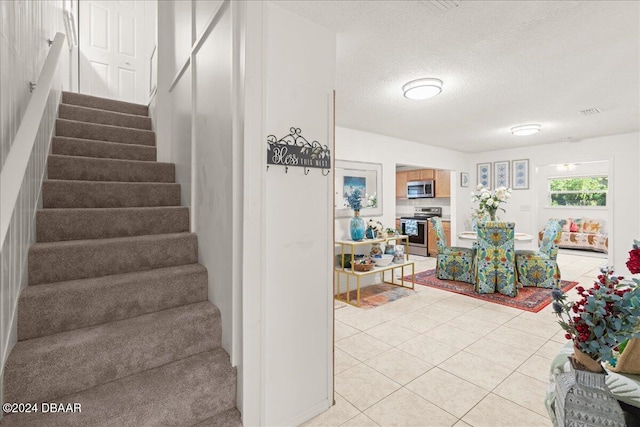 stairs with a textured ceiling and tile patterned floors