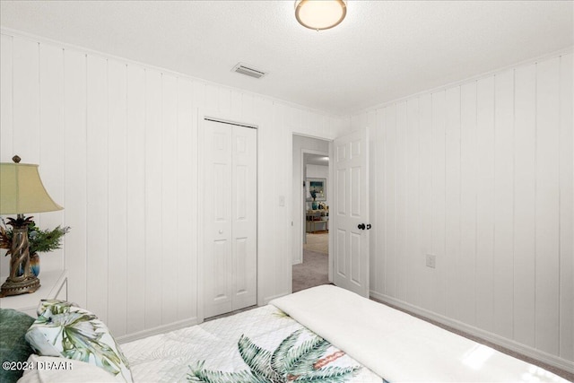 carpeted bedroom featuring wood walls, a textured ceiling, and a closet