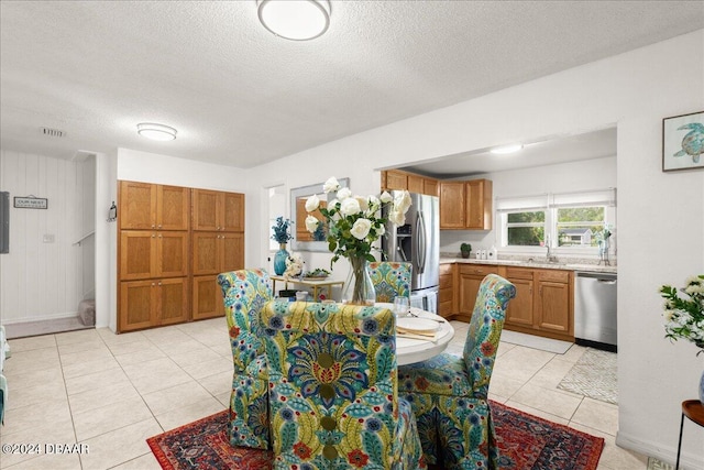 dining room with light tile patterned flooring, a textured ceiling, sink, and wooden walls