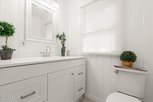 bathroom featuring vanity, wooden walls, and toilet