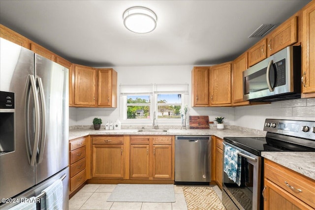 kitchen with decorative backsplash, appliances with stainless steel finishes, sink, and light tile patterned floors