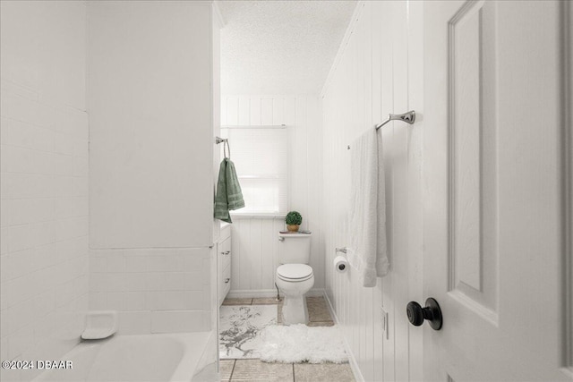 bathroom with wood walls, a tub to relax in, a textured ceiling, vanity, and toilet