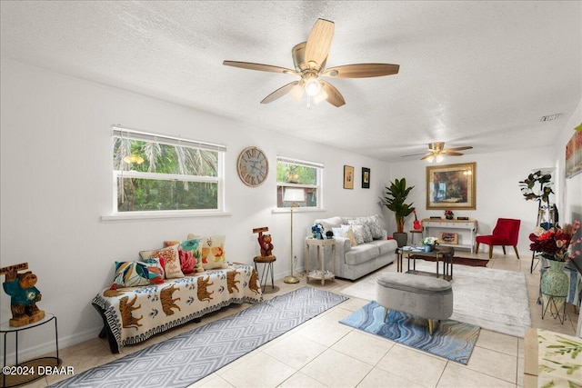 living room featuring a textured ceiling, light tile patterned floors, and ceiling fan