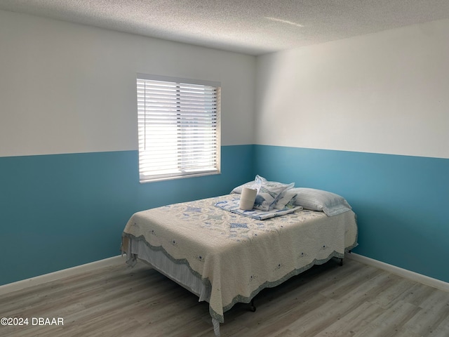 bedroom featuring light hardwood / wood-style floors and a textured ceiling