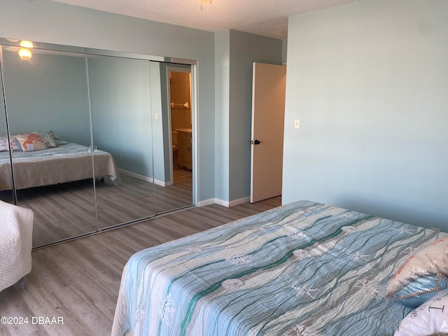 bedroom with hardwood / wood-style flooring, a textured ceiling, and a closet