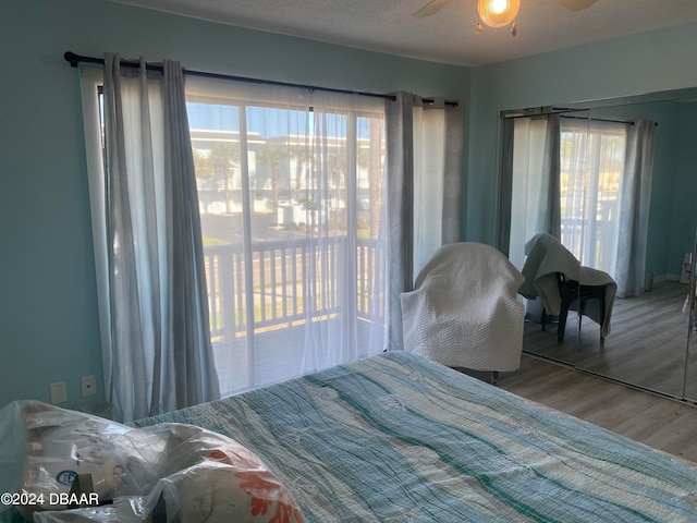 bedroom with access to exterior, a textured ceiling, wood-type flooring, and ceiling fan