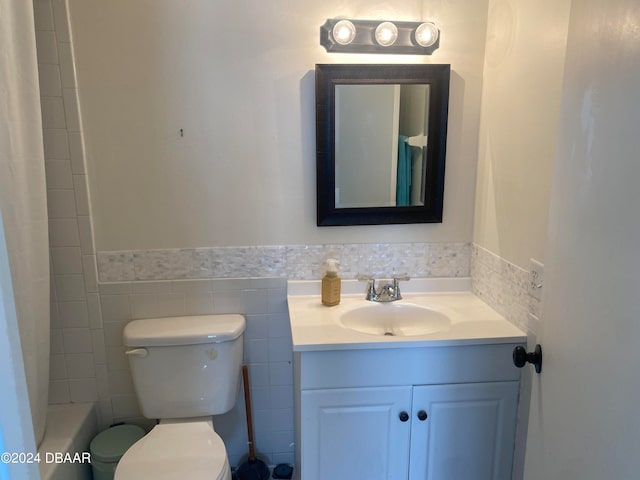 bathroom with vanity, toilet, and tile walls