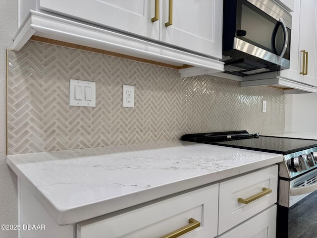 kitchen with light stone countertops, appliances with stainless steel finishes, white cabinets, and decorative backsplash