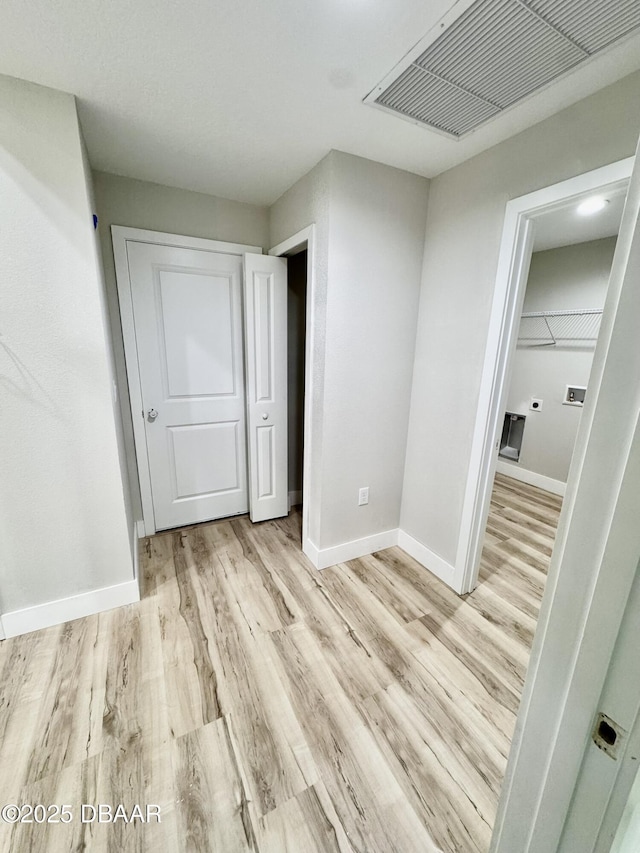 unfurnished bedroom with baseboards, a closet, visible vents, and light wood-style floors