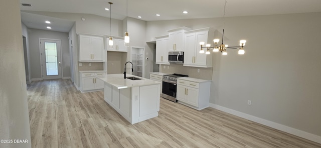 kitchen featuring stainless steel appliances, white cabinets, light countertops, an island with sink, and decorative light fixtures