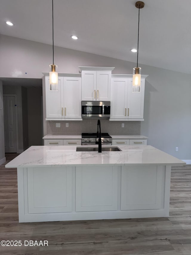 kitchen featuring stainless steel appliances, hanging light fixtures, and an island with sink