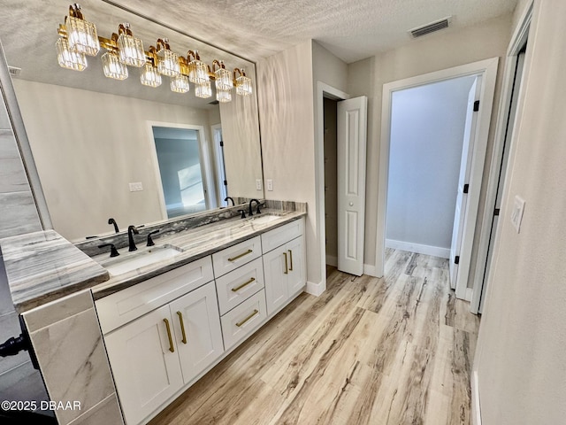 bathroom with double vanity, visible vents, a sink, and wood finished floors