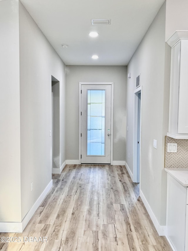 doorway to outside featuring light wood-style floors, visible vents, and baseboards