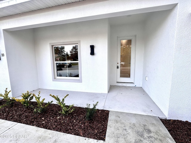 doorway to property featuring stucco siding