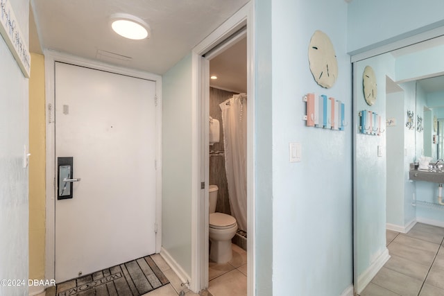 bathroom featuring tile patterned flooring, a shower with shower curtain, and toilet