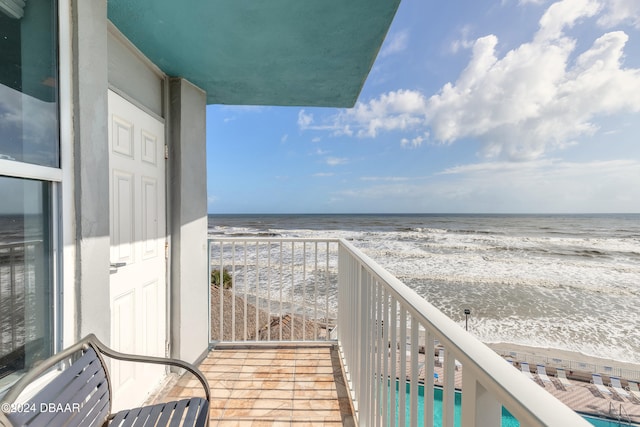 balcony featuring a view of the beach and a water view