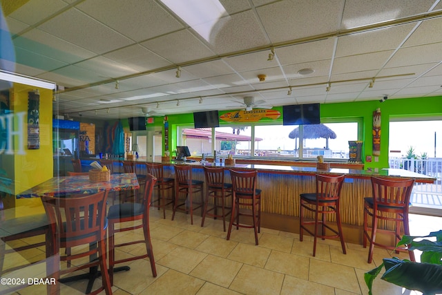 interior space featuring a drop ceiling, light tile patterned floors, ceiling fan, and rail lighting